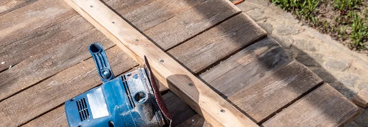 Holzbalken und Schleifgerät auf Brettern