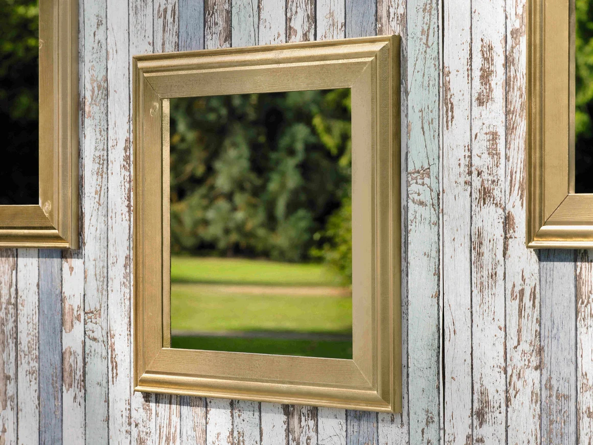 Spiegel mit goldenem Rahmen an Holzwand