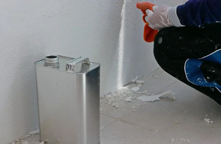 Eine Person entfernt mit einem Schwamm Kleberreste von einer Wand.