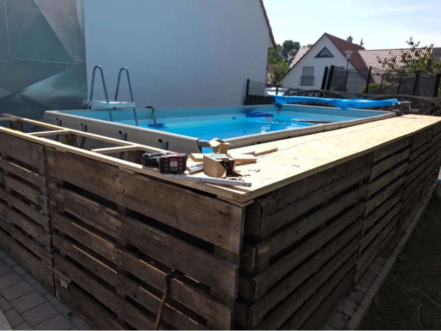 Pool mit Holzrahmen im Bau, Akkuschrauber liegt auf Holz