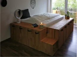 Ein Bett mit integriertem Stauraum aus hellem Holz.