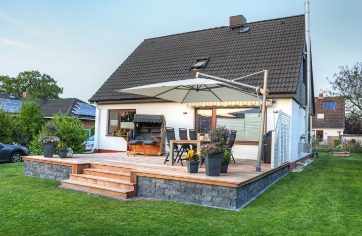 Eine große Terrasse aus Stein und Holz vor einem Haus.