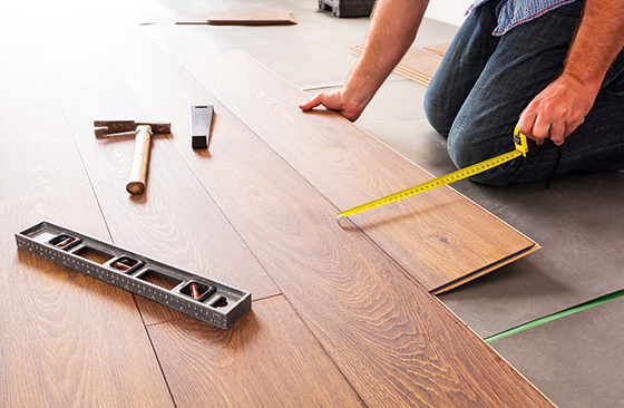 Person verlegt Laminat mit Zollstock