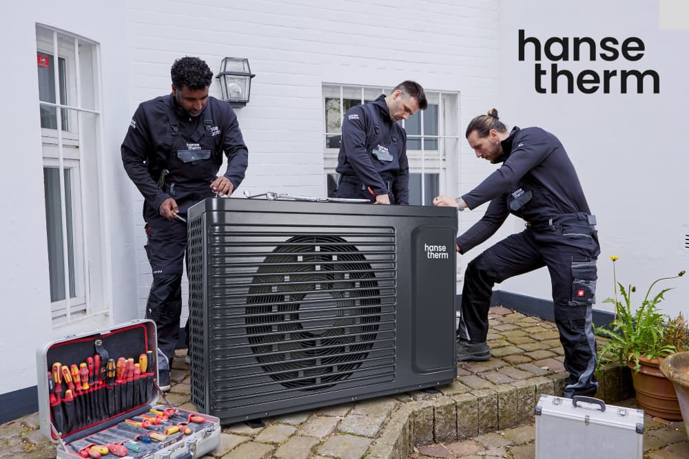 Drei Personen installieren eine Wärmepumpe. Das Logo der Marke hansetherm ist abgebildet.